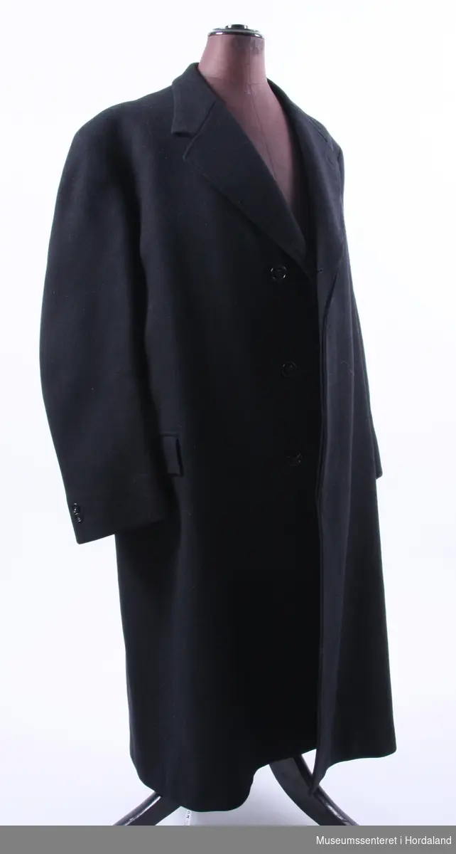 Form: enkeltspent frakk med lange ermer og slag, 3 knappar og knapphol, lommmer med klaff, innvends brystlomme på begge sider.
ein knappen er knekt.
