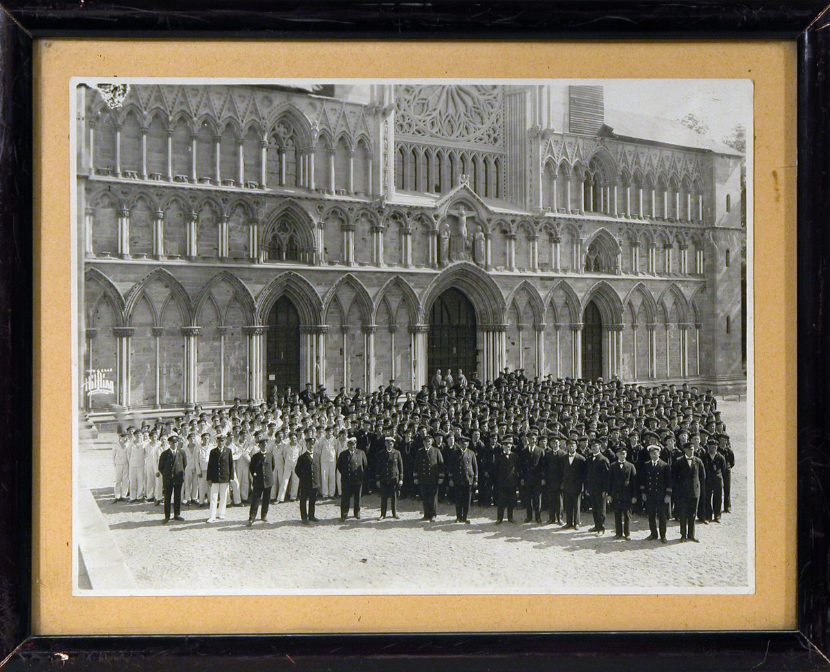 Stor gruppe uniformskledde menn og gutter, offiserer og matroser, oppstilt foran Vestfronten av Nidarosdomen.