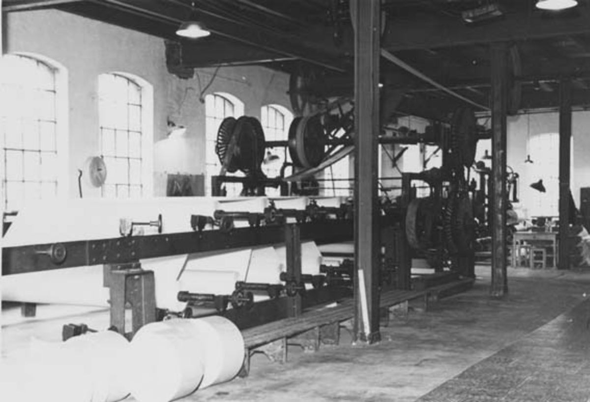 Skjæremaskin (kutter) ved Drammenselvens Papirfabrikker i Modum, Buskerud.  Denne maskinen var produsert av firmaet Walmsley i Bury i England.  Ifølge informant Øyvind Haugen skal den ha vært i bruk til en Jagenberg-maskin (jfr. SJF-F. 000006) ble installert, antakelig i første halvdel av 1950-åra. Fotografiet ble tatt i 1953.  Det er nesten identisk med SJF-F. 000017. 