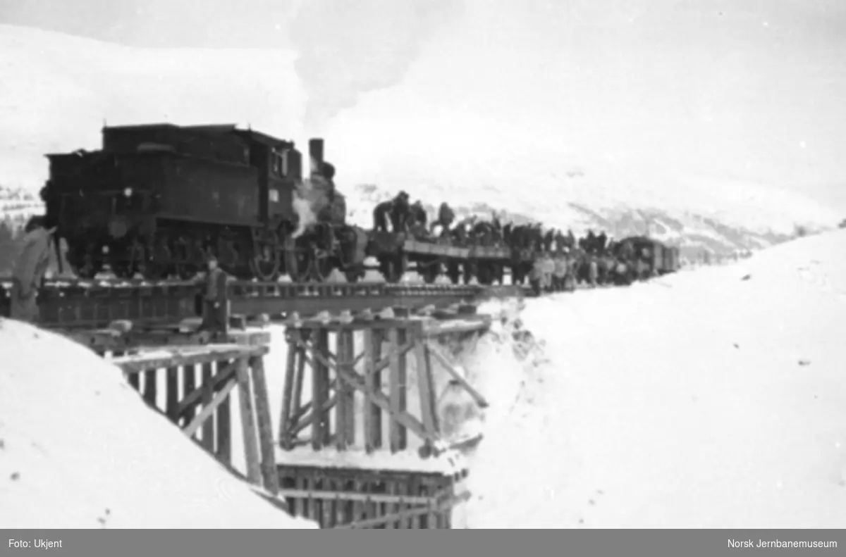 Damplokomotiv med grusvogner og mannskap på provisorisk bru over Kumra, rett nord for Drevja stasjon