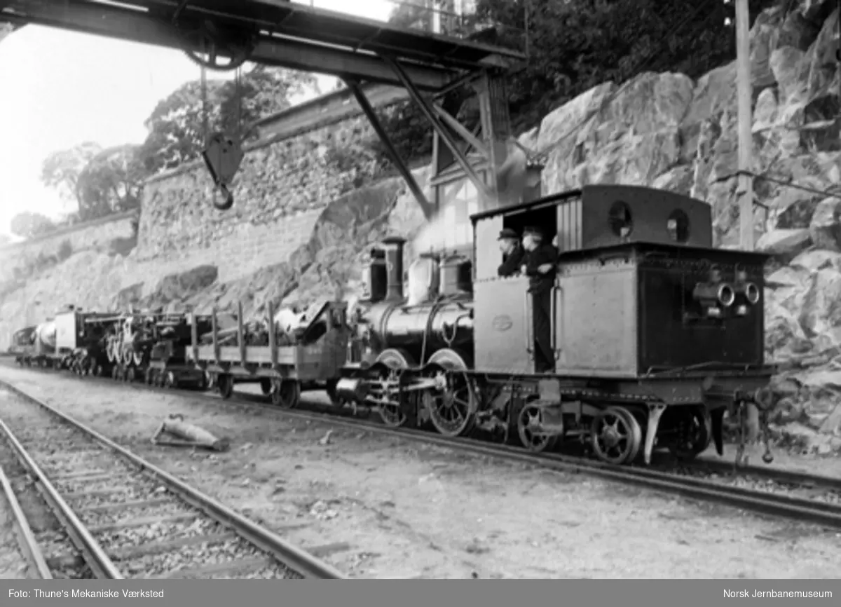 Damplokomotiv type VI nr. 50 "Hygeia" foran et tog for transport av normalsporet lokomotiv (type 24?) under Akershus
