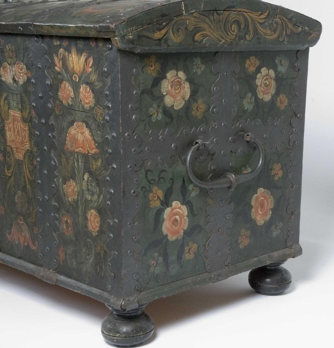 Kiste med buet lokk og heldekkende rosemaling, hvorav mye er senere tilføyelser eller restaureringer. Kulebena er også sekundære.