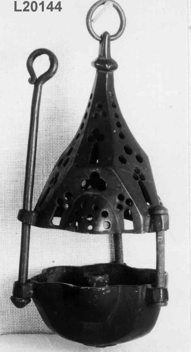 Bronse. 6 sidet. 3 av sidene med kuleformet utvidelse. Skål med pipe i centrum. Firpassformen viser hen på slutten av middelalderen. Den skjematiske og grove utførelse tyder på hjemlig produksjon. Ligger nær å gjette på Tunsberg. Etter reformasjonen er en lysepipe satt inn. Mulig denne lysestake har hengt etter en snor og likeledes den lange glidestangen