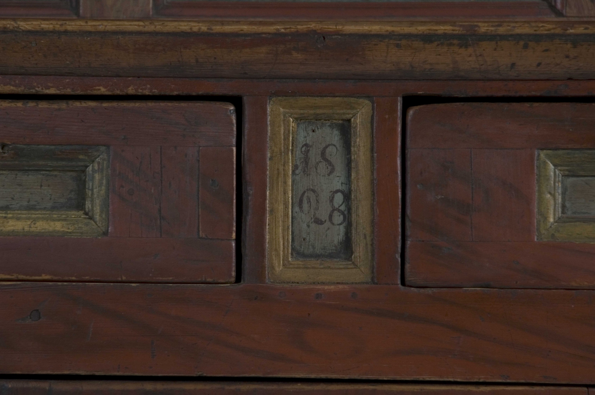 Doble dører oppe, to skyvedører på midten, en dør nede og to skuffer. Malte moriver: to adelsmenn og to blomster med nakne figurer oppi. Samson og løven på nedre skapdør. Marmorering i nisjen. Skyvedørene er dekorert med hester, kuer og geiter samt hus og en kirke.