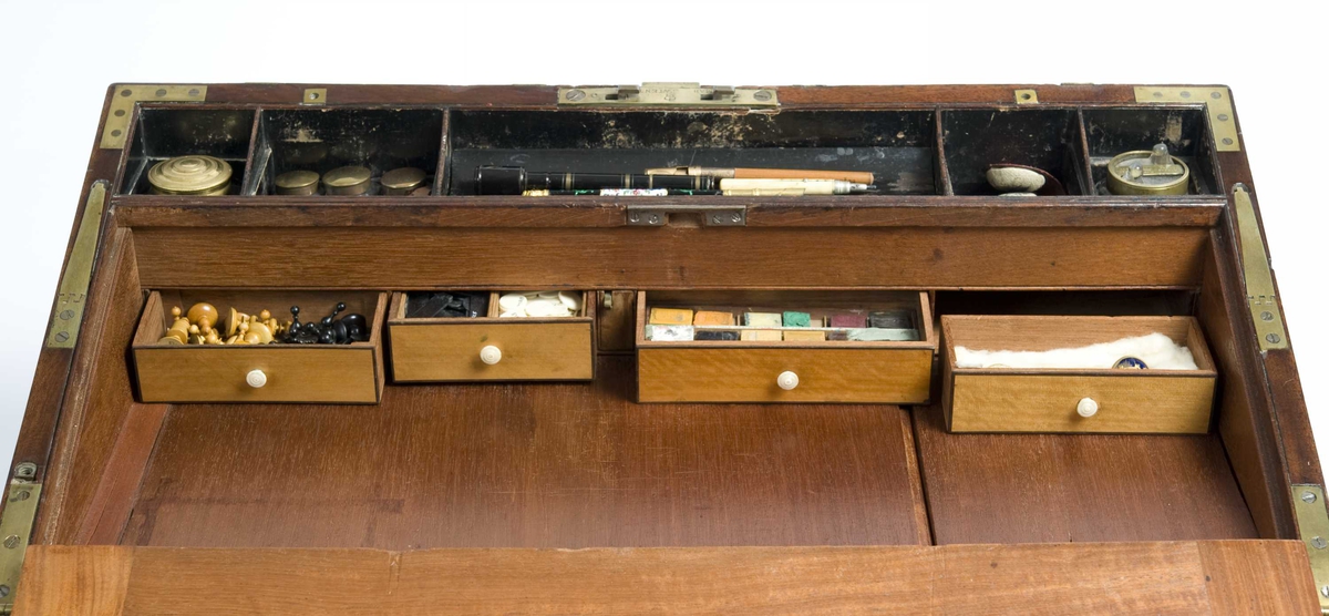 Skrin med skriveskive i lokket, skuffer på kortsidene og en mengde skjulte rom. Rommene innehoder gjenstander for bruk ved reiser: Barberutstyr; måleinstrument; bestikk; hygieneartikler; røykeutstyr; fiskeutstyr; duelllpistoler med mer.