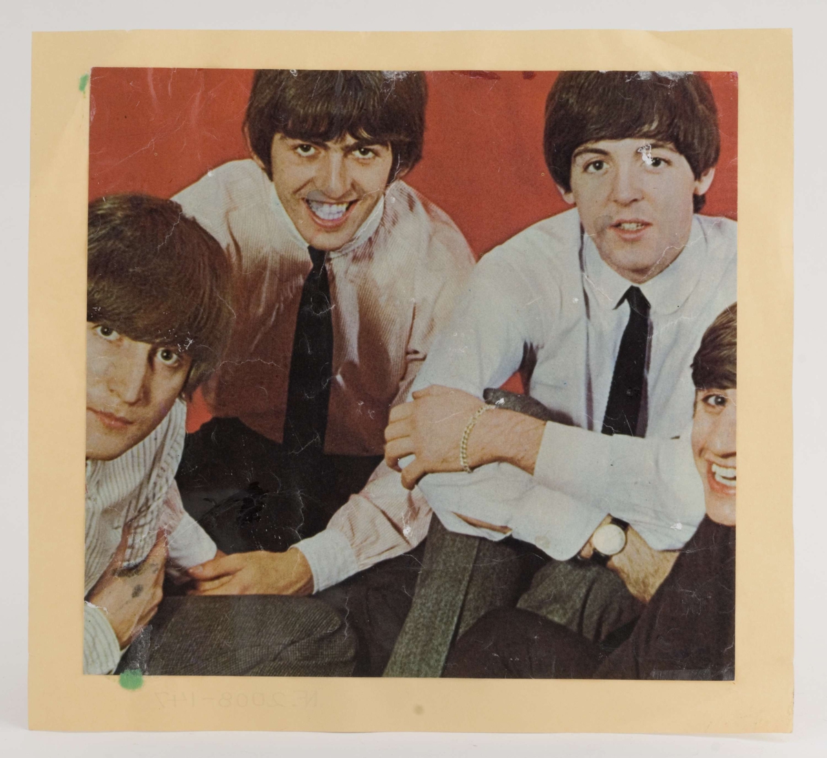 Fargefoto av Beatles-medlemmer limt på blekgult papir

