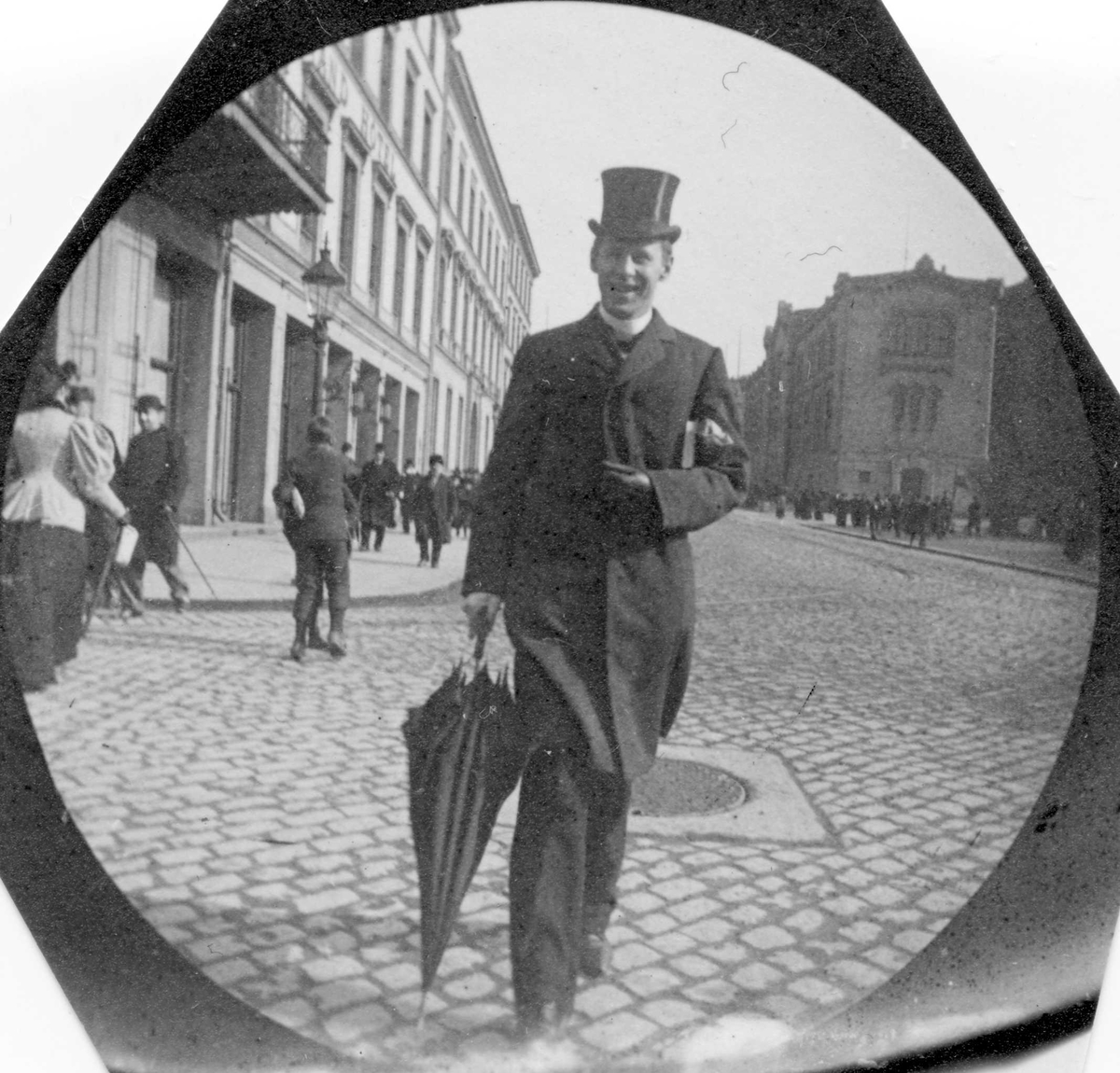 Henrik Reimers med flosshatt og paraply, spaserer på Karl Johans gate, Oslo,