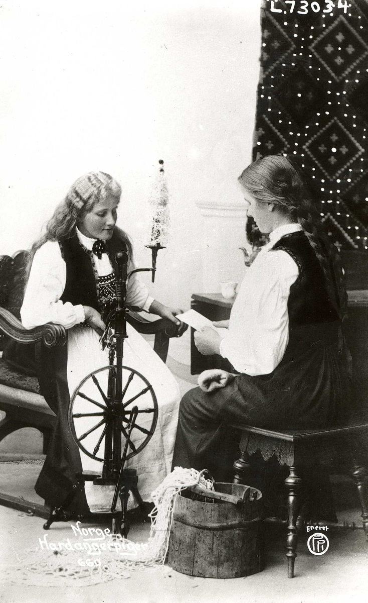 Fotografi av to kvinner som spinner. Drakt fra Hardanger.