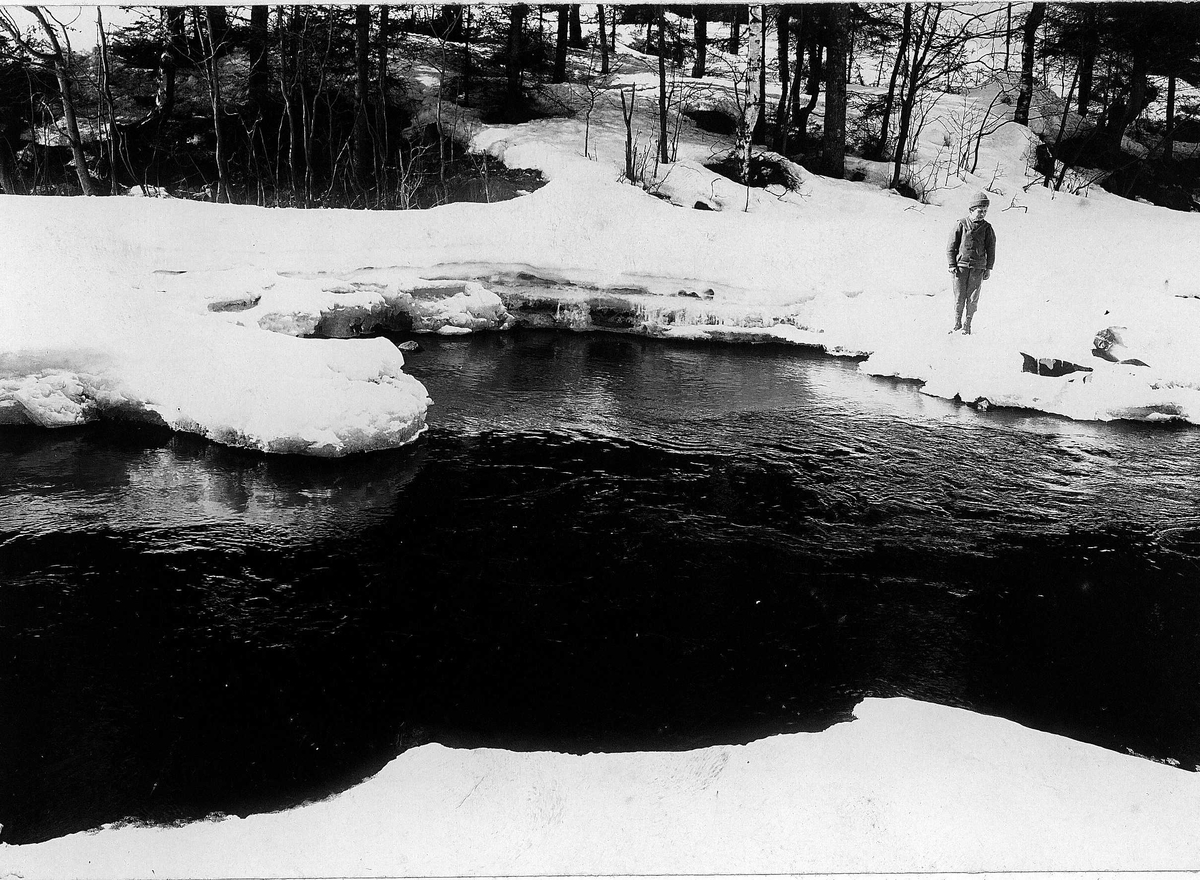 Vinter, gutt ved åpen elv, ukjent sted.
Serie tatt av Robert Collett (1842-1913), amatørfotograf og professor i zoologi. 