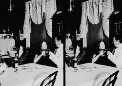 Interiør, mann og kvinne sitter ved bord og skåler, Axel Q. 