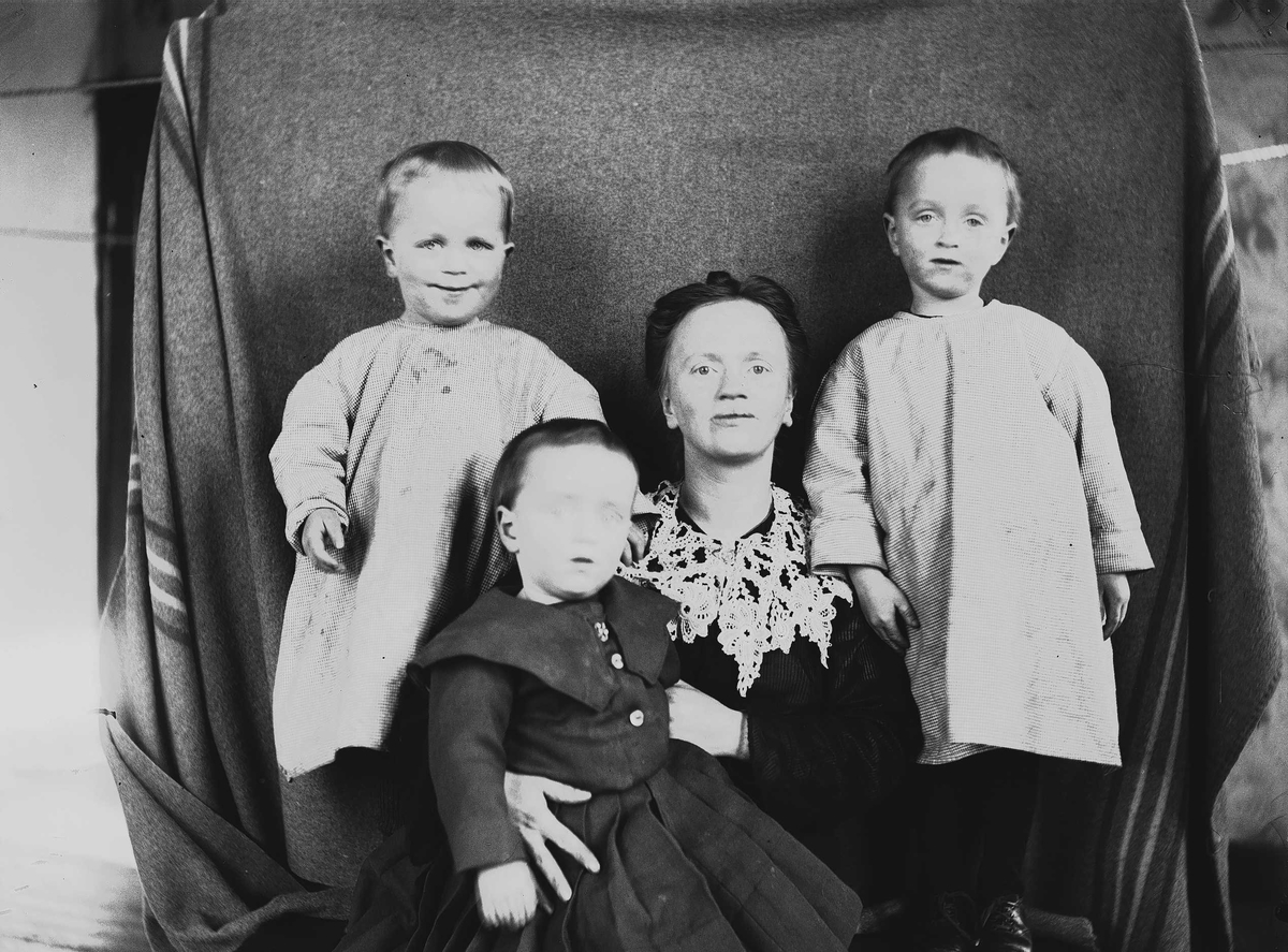 Portrett av Thor, Halvor Nicolai  (ant. foran), mor Margrethe og Simon Q. Wiborg, Digerud, Frogn, Akershus, mars 1907. Fotografert mot opphengt bakteppe.