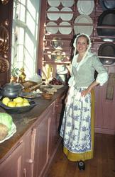 Vert i bydrakt på kjøkkenet med mat på bordet i Chrystiegård