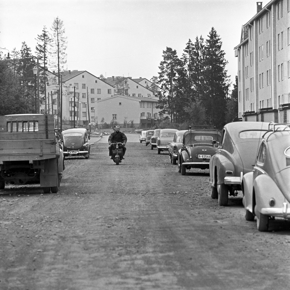 Serie. Parkeringsvansker i de nye boligområdene i Oslo, Manglerud og Lambertseter. Trehjulsykkelen må parkeres på gresset. Manglerud, Rugveien. Fotografert august 1958.