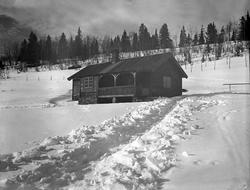 En hytte ligger i et vinterlandskap. Fotografert påsken 1934