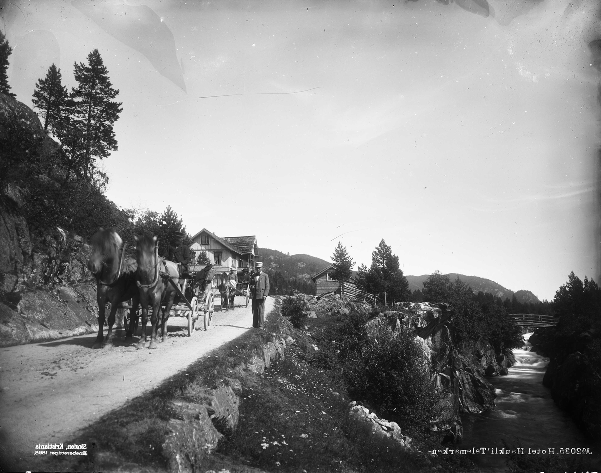 Hestekjøretøyer på vei foran Haukeli hotell, Vinje, Telemark. Nærmest en kalesjevogn trukket av to hester, den andre er ei stolkjerre antatt med sete på trefjærer. 