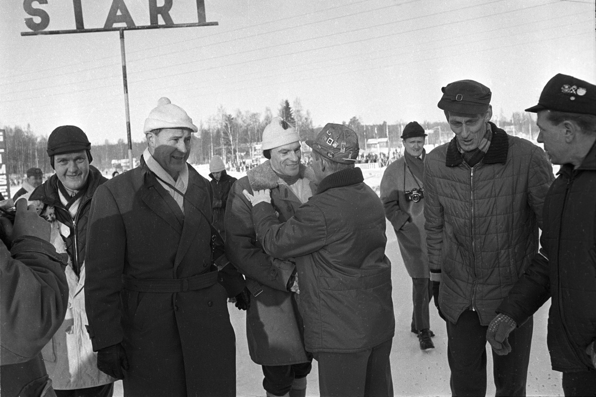 Finsk skiløper i midten blir gratulert i målområdet. Svenska Skispelen i Falun i 1967.