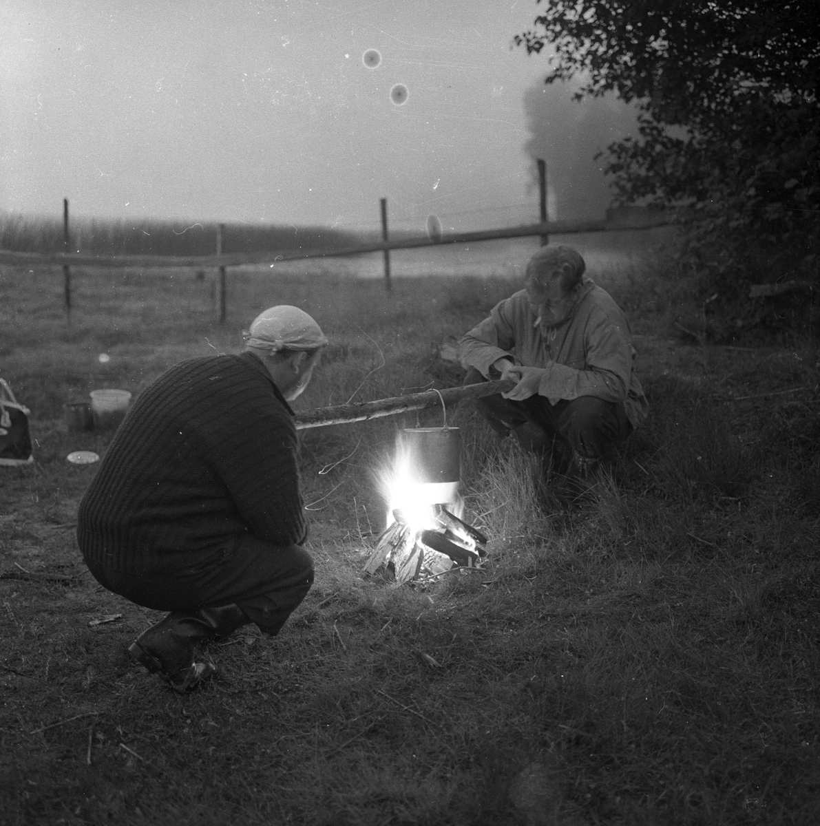 To menn koker kreps på bål.
Fotografert 1958.