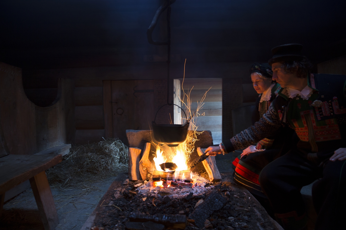 Formidlere i setesdalsdrakt tilbereder matretten spa. Julefeiring i "Sagastua", kopi av årestue fra Kjelleberg i Setesdal. Julemarkedet på Norsk Folkemuseum, 1. desember 2013.
