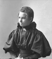 Portrett, Kathinka Andvord i svart drakt, smykke formet som 