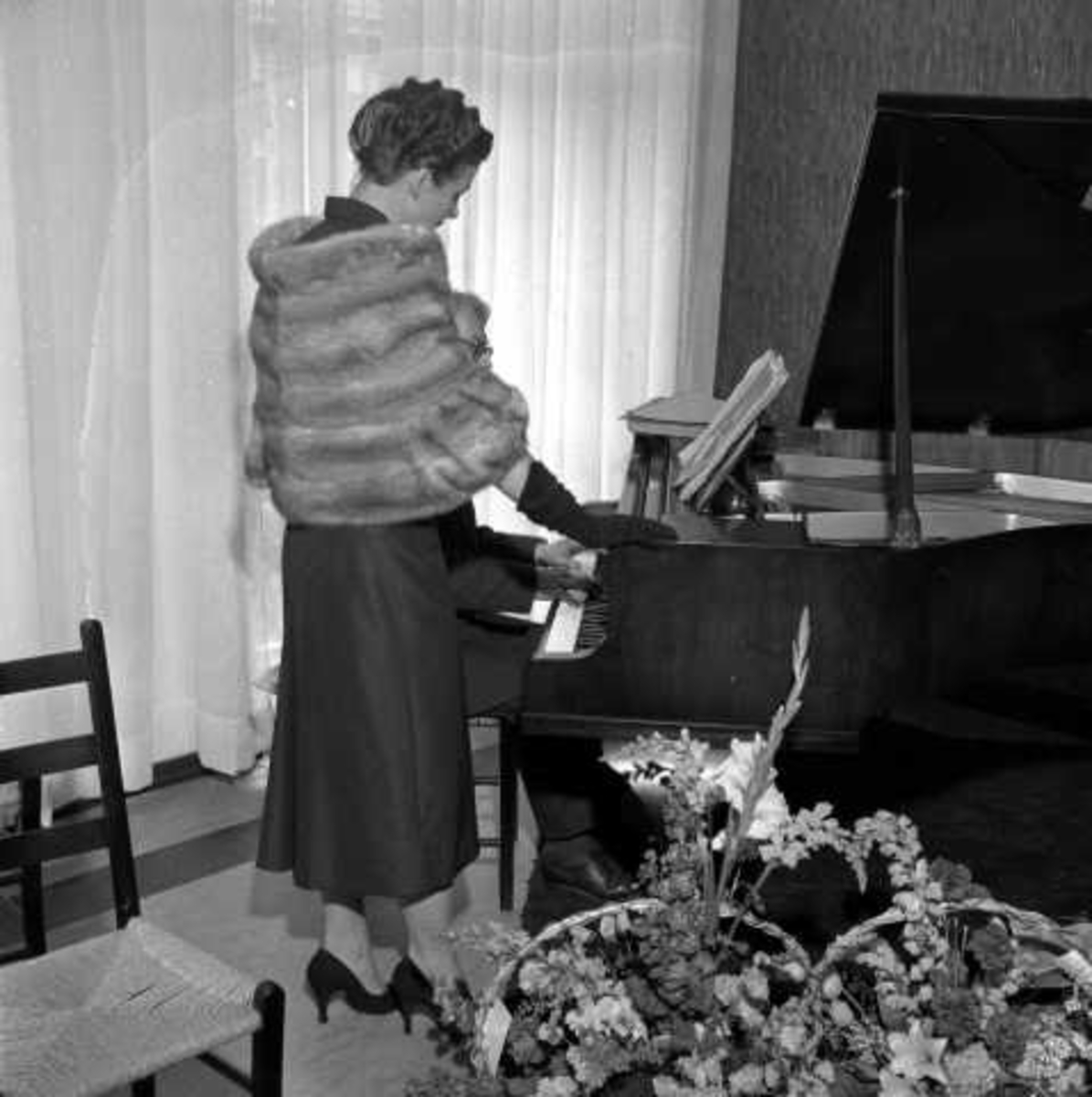 "Pels Backer"`s 100 års-jubileum, juni 1956. Kvinne med pels-stola ved flygel.