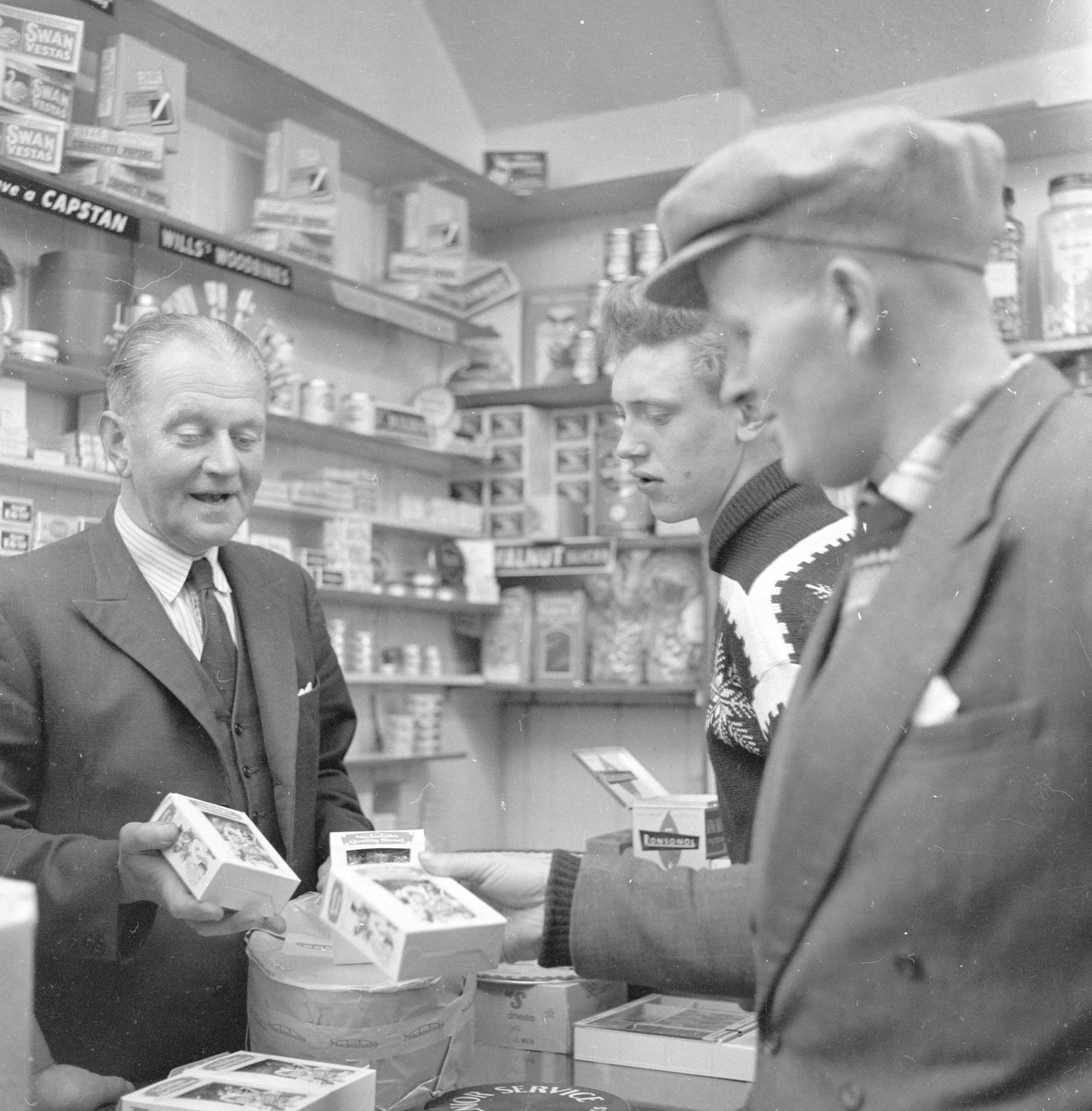 Pigghåfiske på Shetland.
Shetland, 14-22. mai 1958, kunder og innehaver i butikken.
