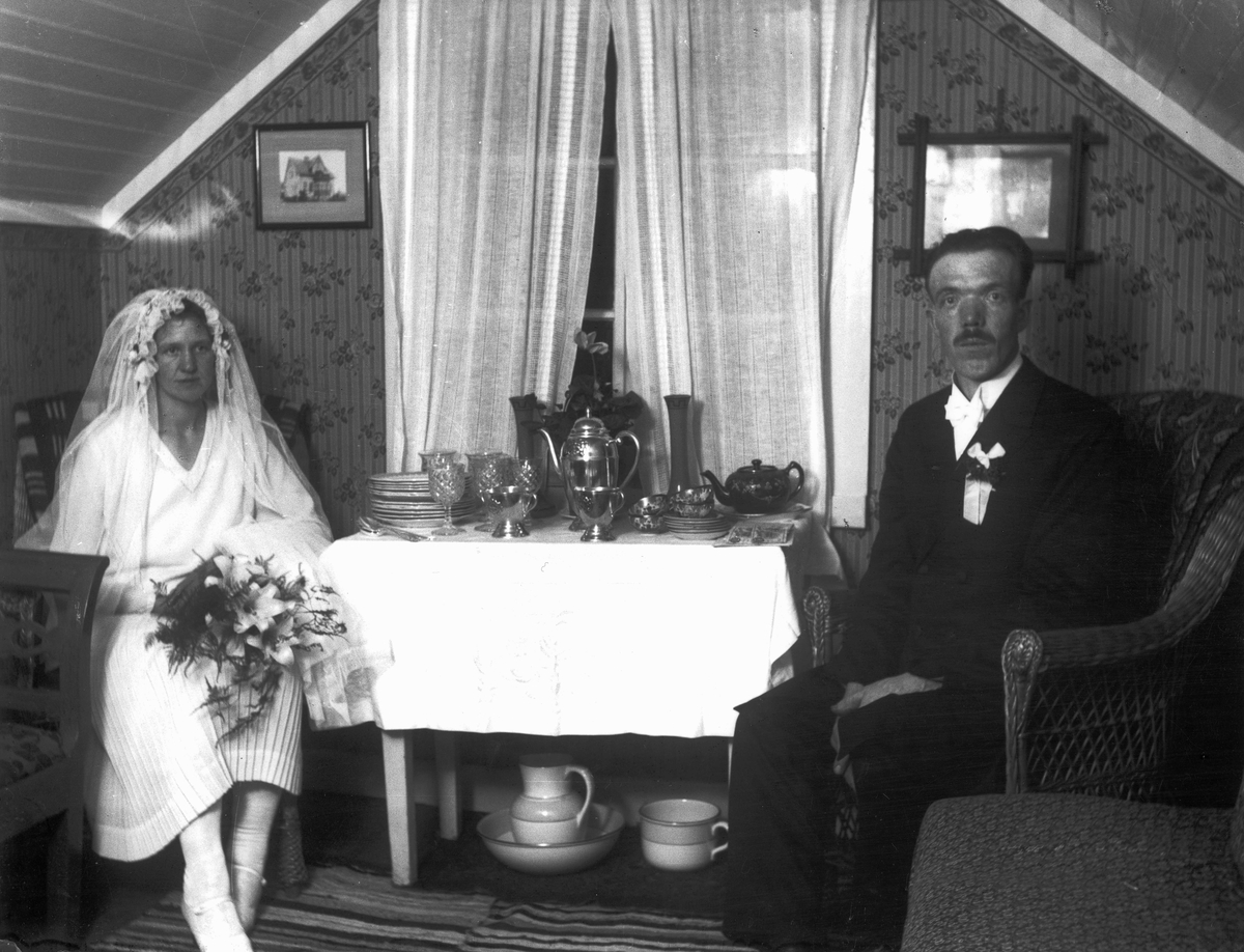Brud och brudgum som sitter på var sin sida om ett bord med bröllopspresenter.