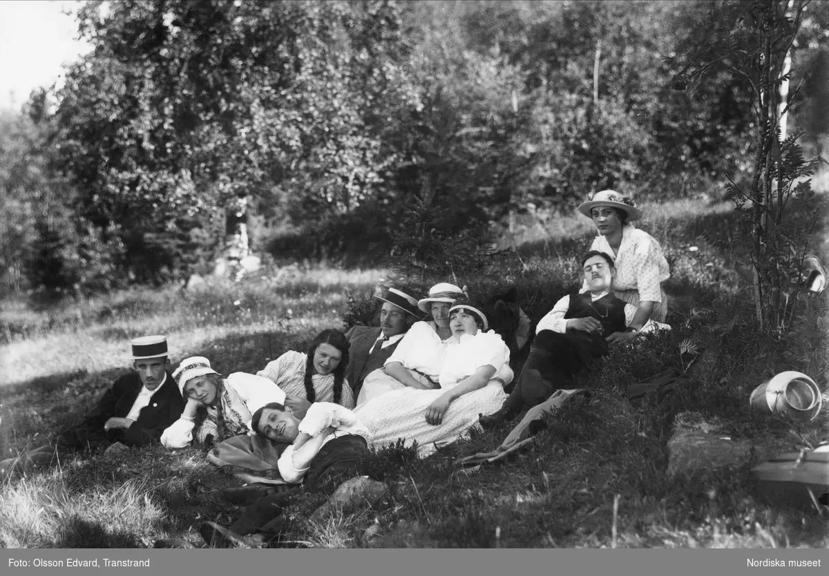 "Där man mår som pärla i guld." Sommarklädda ungdomar vilar i gräset i en skogsbacke. Dalarna, Lima / Transtrand socken.