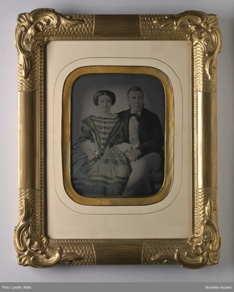 Dubbelporträtt, Sven Alarik Bergström, förste revisor, och hans hustru Flore Joséphine Constance, f. Pontus. Klockkedjor, ringar och örhängen förgyllda. Ambrotyp, kolorerad, i förgylld träram.
Nordiska museet inv.nr 209624.