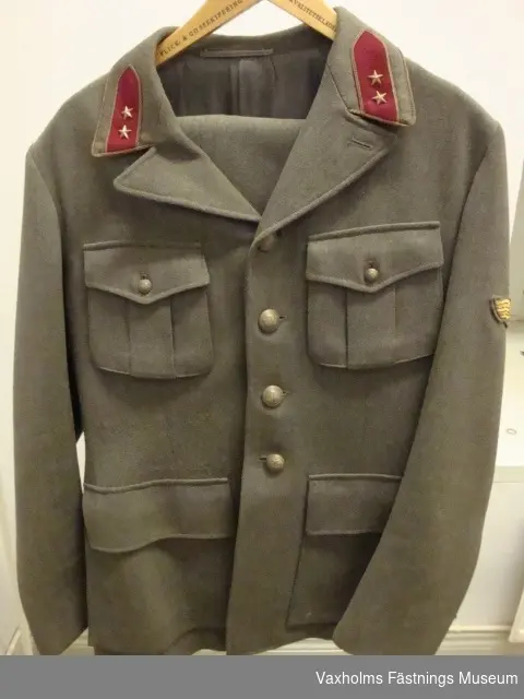 Uniform m/42. Vapenrock och byxor. Gråkommisgrön diagonal med löjtnants gradbeteckning. På höger ärm flygtecken m/15 (flygspanare).