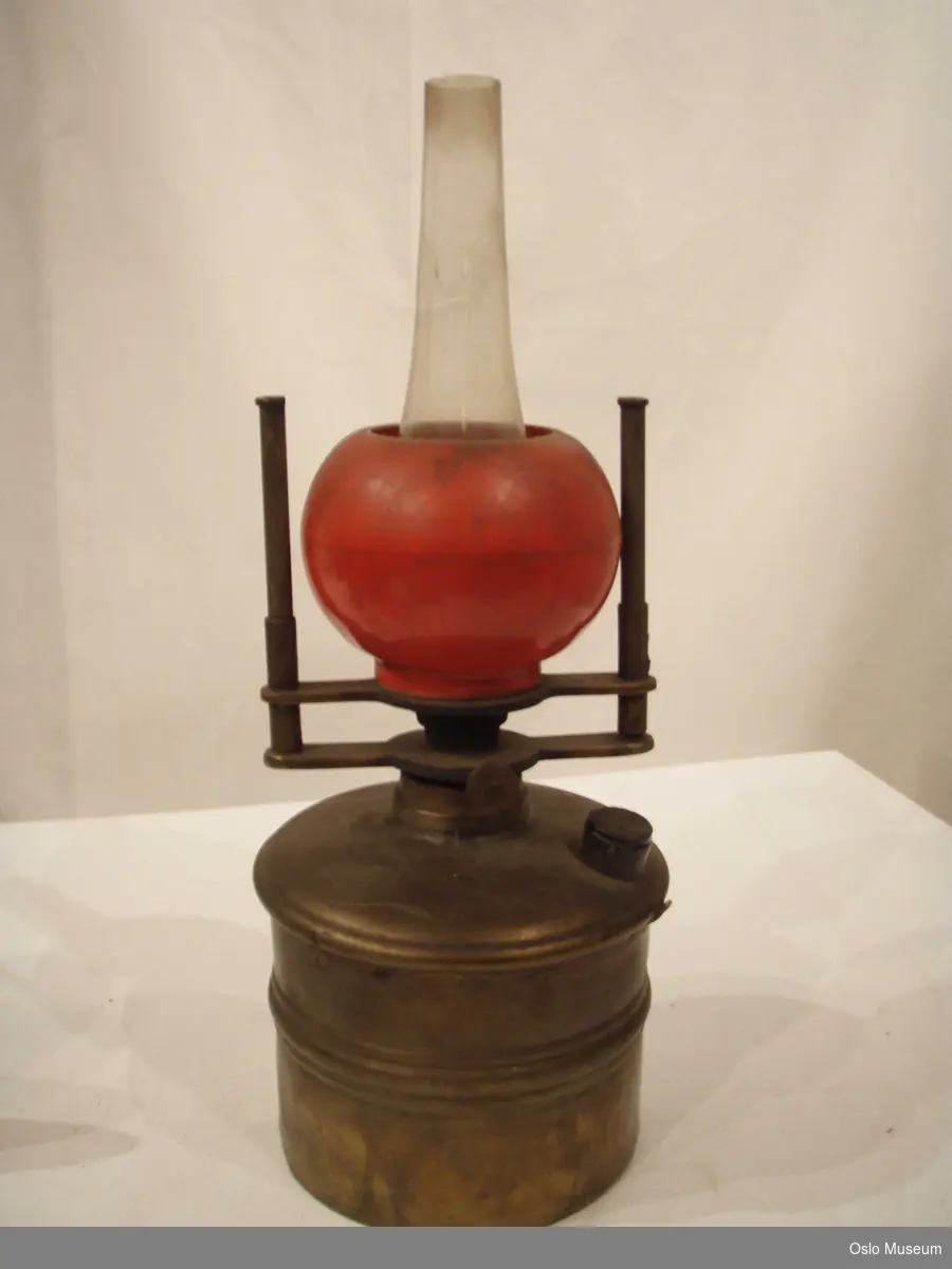 Oljelamper med messing oppheng og kolbe. Lampeskjerm i rødt glass og lampeholder i klart glass.