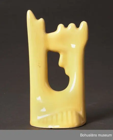 Figur föreställande stiliserad gulglaserad tupp. 
Märkt med femkantig påklistrad lapp med firmamärke.