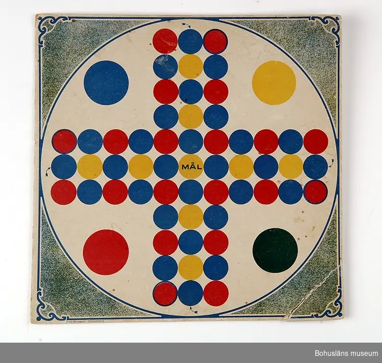 Ett Fia-spel med spelpjäser. Kartong med tryck på ena sidan. 
Spelplan med blå,  gula och röda rundlar, i mitten med texten "MÅL".
Nere till vänster tryckt LITO RYSTEDT GÖTEBORG
På basidan märkt med blyert: Abrahamson.

Föremålet har använts av familjen Abrahamson i deras sommarstuga i Sundsandvik, byggd 1939.
För ytterligare upplysningar om förvärvet, se UM031385.