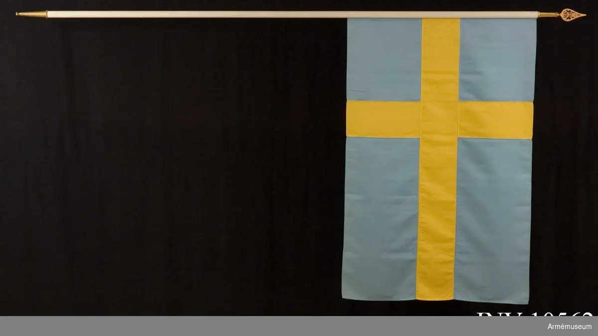 Grupp B I.

Duk av blått och gult siden, s k korsflagga. Fodral av blått kläde är märkt på den undre fickan: "Int 2". Fickan innehåller spetsen med Gustav V:s namnchiffer.