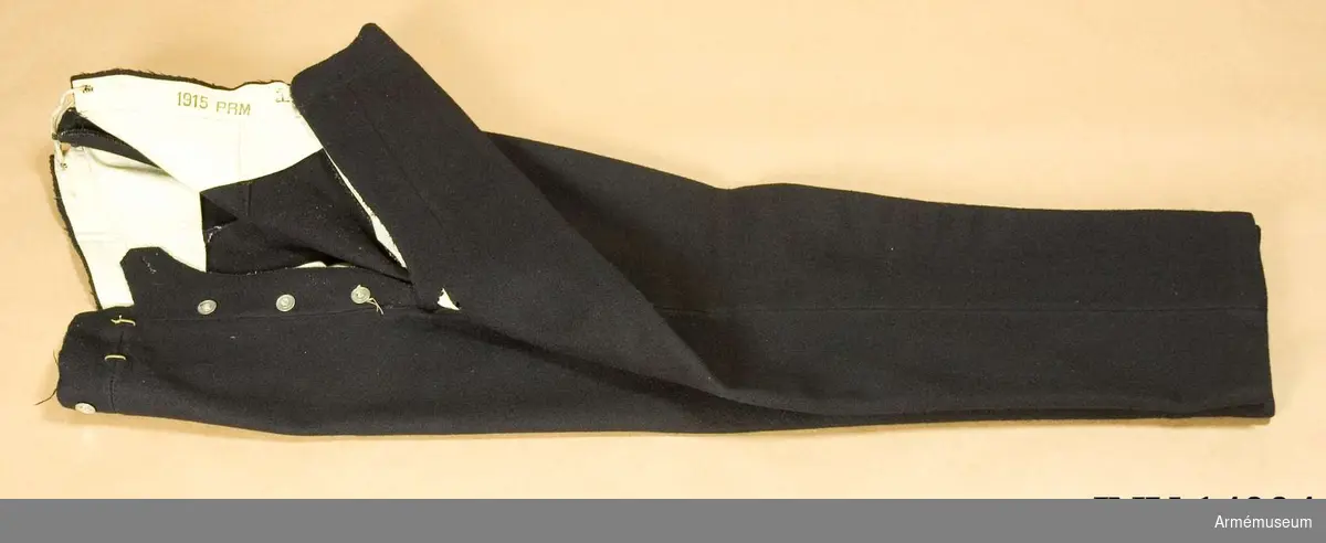 Grupp C I.
Danska bukser. Av mörkblått kläde. Två fickor på sidan och på baksidan spänntamp av kläde m spännen. Järnknappar, 3 st på sprundet, 6 f hängslen. Foder av vitt tyg m stämpel "PRM" =prövemaessigt (=modellenl.), "1913", "3 A.B." =3e art.bataljon. (Munderingsvaesenet i Fredstid, Köbenhavn, 1908, sida 30 par. 54, sida 33 par.65).
Enl papperslapp från Töjhusmuseet tillhör byxan "Forplejningskorpset. Menig uniform" m efter stämpel på foder "3 A.B." =3e artilleribataljonen.
LITT Danske Uniformer, Haer og Flaade, tegnede av Rs. Christiansen, Köbenhavn, Krigsministeriet og Marine ministeriet, trol 1912. Bild i färger: "Forplejningsassistent, alm. tjenestedragt". Dessa byxor lika med de på bilden.Enl Granberg 1951.