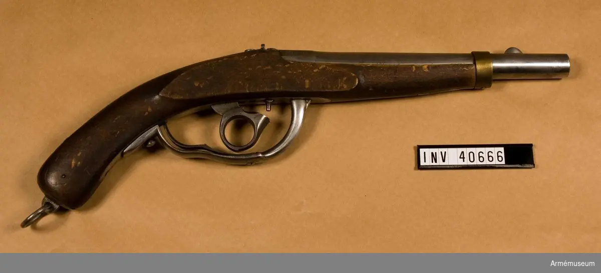 Grupp E III.
Med slaglås.
Pistolen har järnbeslag förutom näsbandet som är av mässing. Den har underliggande slaglås, där hanen har ringformat tumgrepp. På kammarstycket står dels en oläslig stämpel i form av monogram, M -1841, B- 1842-12, vilket kan betyda modell: 1841, tillv. 1842, tillverkningsnummer 12. Det senare numret förekommer på pistolens samtliga delar.