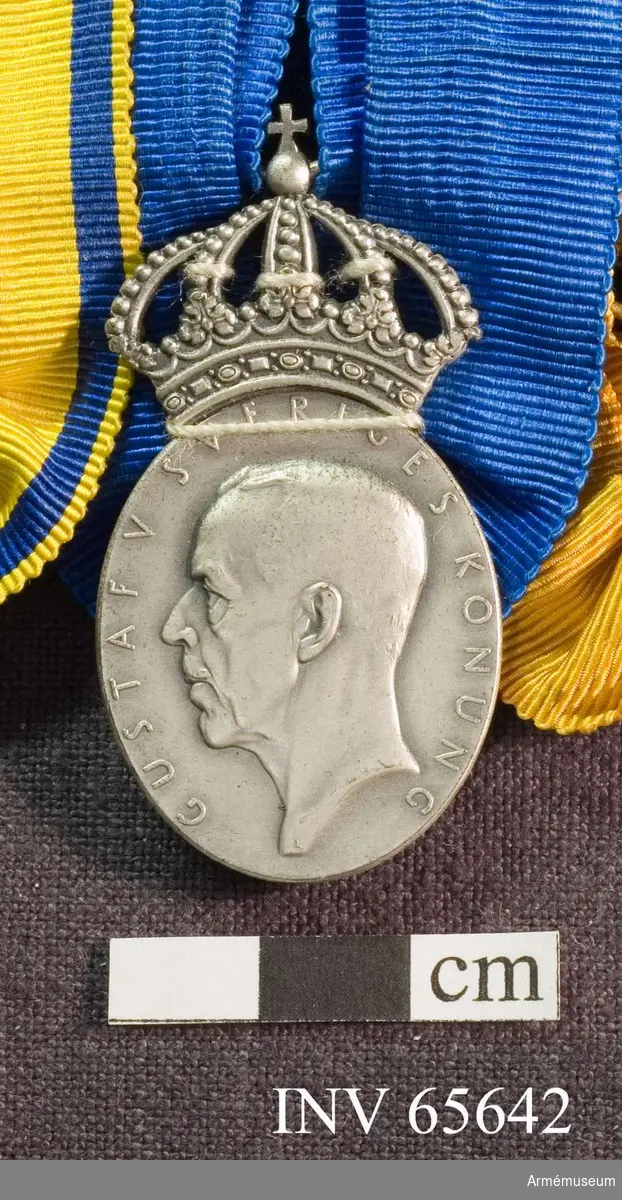 Grupp M II.
Medaljen är en oval med en kunglig krona ovanför. Åtsidan har kung Gustav V i profil samt "GUSTAV V SVERIGES KONUNG" utmed kanten. Frånsidan har tre öppna kronor - två över en - bevingad granat samt "RIKSLUFTSKYDDSFÖRBUNDET" utmed kanten. Under granaten en rektangel med "T. GUSSING 1942". Under den en namnstämpel "S & Co" (tillverkare) och fyra kontrollstämplar. Medaljbandet är blått och rynkat på ena långsidans mitt och hopdraget på att bandet har blivit U-format. På baksidan ett likadant behandlat band, fast dubbelvikt på längden.