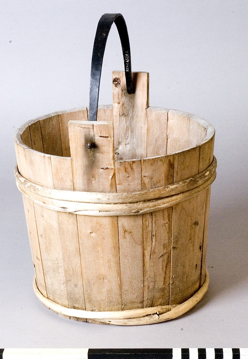 Spann av trä med smitt handtag av järn. Spannen utförd i laggteknik och hålls samman med två band av eneträ.