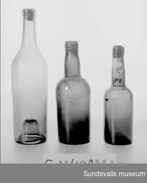 SuM 4982:1-3 tre flaskor. SuM 4982:1 och 4982:3 har gröntonat glas och kork och mäter 26,5 cm, respektive 19 cm på höjden. SuM 4982:2 har bruntonat glas och är 20 cm hög.
