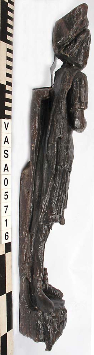 Skulptur föreställande mansfigur iklädd romersk rustning. Huvudet pryds av en lagerkrans som avtecknar sig mot ett stort snäckskal. Ansiktet med den rynkade pannan är slätrakat. Figuren är iförd thoraxrustning med en utmed ryggen nedhängande mantel. Manteln är draperad i en smal sträng snett över bröstet, och sitter fästad med ett spänne på höger skuldra.



Figurens huvud och överkropp är helt vridna mot vänster, underkroppen endast till hälften. Benen är frontalställda. Höger arm hålls vinkelrätt böjd över bröstet. Kroppstyngden vilar på höger ben, medan vänster ben hålls böjt. Upptill är bakstycket framdraget i en enkel, rektangulär "huvudplatta".



Figuren står på en sockel, som framtill pryds av en djurmaskaron, ett groteskt lejonansikte eller dylikt. Maskaronen har spetsiga rovdjurständer och rundade öron. På sockelns mitt finns en banderoll med en namninskription. Bokstäverna R och O är tydligt skönjbara på höger del av bandet, medan bokstäverna på bandets vänstra del är utplånade.



Skulpturens baksida är rak och uppvisar tre snedställda, olika djupt liggande fält. De tre fälten, som utgör anliggningsytor, ger skulpturen en trappstegsformad profil.



Skulpturen är mycket sliten. Figurens högra hand är kraftigt skadad. Vänster arm med vidhängande del av manteln saknas.



Text in English: Sculpture representing a male figure wearing Roman armour. The figure has a laurel-wreathed head, set against a large sea shell. The face is clean-shaven and the forehead wrinkled. The figure is wearing thorax armour, with the mantle hanging down the back and draped across the chest from the right shoulder to the left side of the waist in a narrow swathe.



The head and upper part of the body are turned wholly, the lowwer part of th ebody halfway, to the left. The legs are posed frontally. The right arm is held bent at a right angle cross the chest, its hand is badly damaged. The left arm and the part of the mantle that covers it has fallen off. The body rests on the right leg while the left is bent.

The upper part of the back extends upwards in a simple, rectangular  "head board".



The figure stands on a plinth which is decorated by a grotesque mask, reminiscent of a lion head with teeth and rounded ears. In the centre of the plinth is a broad label with a name inscription. As we view it from the front no letters can be seen on the left but the letters R and O are clearly visible to the right.



The sculpture''s back has three obliquely placed flat surfaces of different depths, that are areas of attachment. The flat surfaces make the sculpture looks like a step-ladder in profile.

The sculpture is badly worn. The figure''s right hand is badly damaged. The left arm and the part of the mantle which covers it is missing.