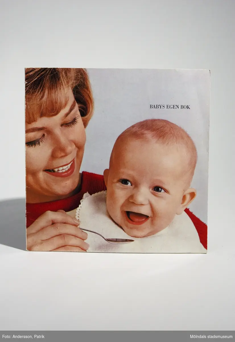 Handbok - "BABYS EGEN BOK", utgiven 1965 av Semper AB i samarbete med barnläkare och sjuksköterskor. Tryckeri: Stig Arbman AB.Bokens framsida är ett färgfotografi på en kvinna som matar en baby. Där står också bokens namn.Fotografiet fortsätter på bokens baksida. En del av baksidan är vit. Där framgår det att boken är:"5:e upplagan. 500:e tusendetPris 3:50Stig Arbman AB/1965"Handboken innehåller tips & råd kring barnets skötsel och mat. Längst bak i boken finns sidan: "Mammas Dagbok", där hon kan fylla i:"Du föddes denklockanDu vägde...och var...cm långDu döptes denDu fick mammas mjölk till Du varDu satt utan stöd vidoch reste Dig upp vid De första stegen tog Du när Du varDet första Du sa varoch då var DuDe första tänderna kom när Du varVaccinationerBarnsjukdomar"MåttLängd: 199 mm, Bredd: 199 mm, Höjd: 3 mm
