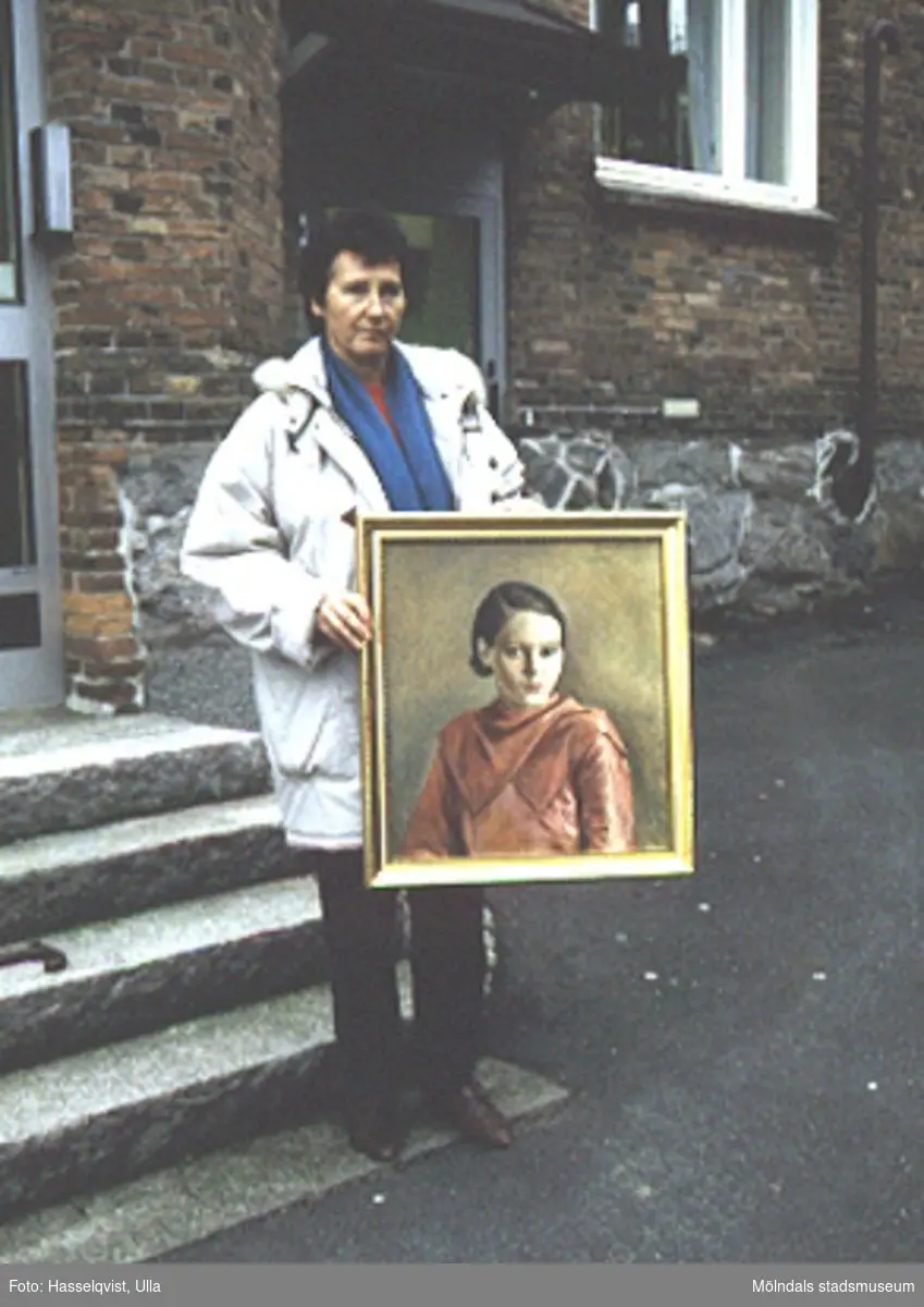Målning utförd av Teodor Lindbäck, Lindome, 1934. Olja på duk. Porträtt av Britta Hagman, f. Johansson 1914, d. 1963. Tavlan ägs av dottern Britt-Marie Hagman, som håller upp den på fotot.