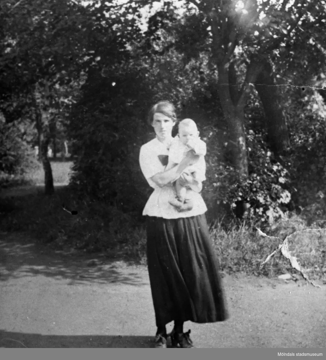 Givaren Knut Anderssons mor Olga Andersson med sonen (och senare storebror) Evald i famnen. Krokslättsparken 1919.