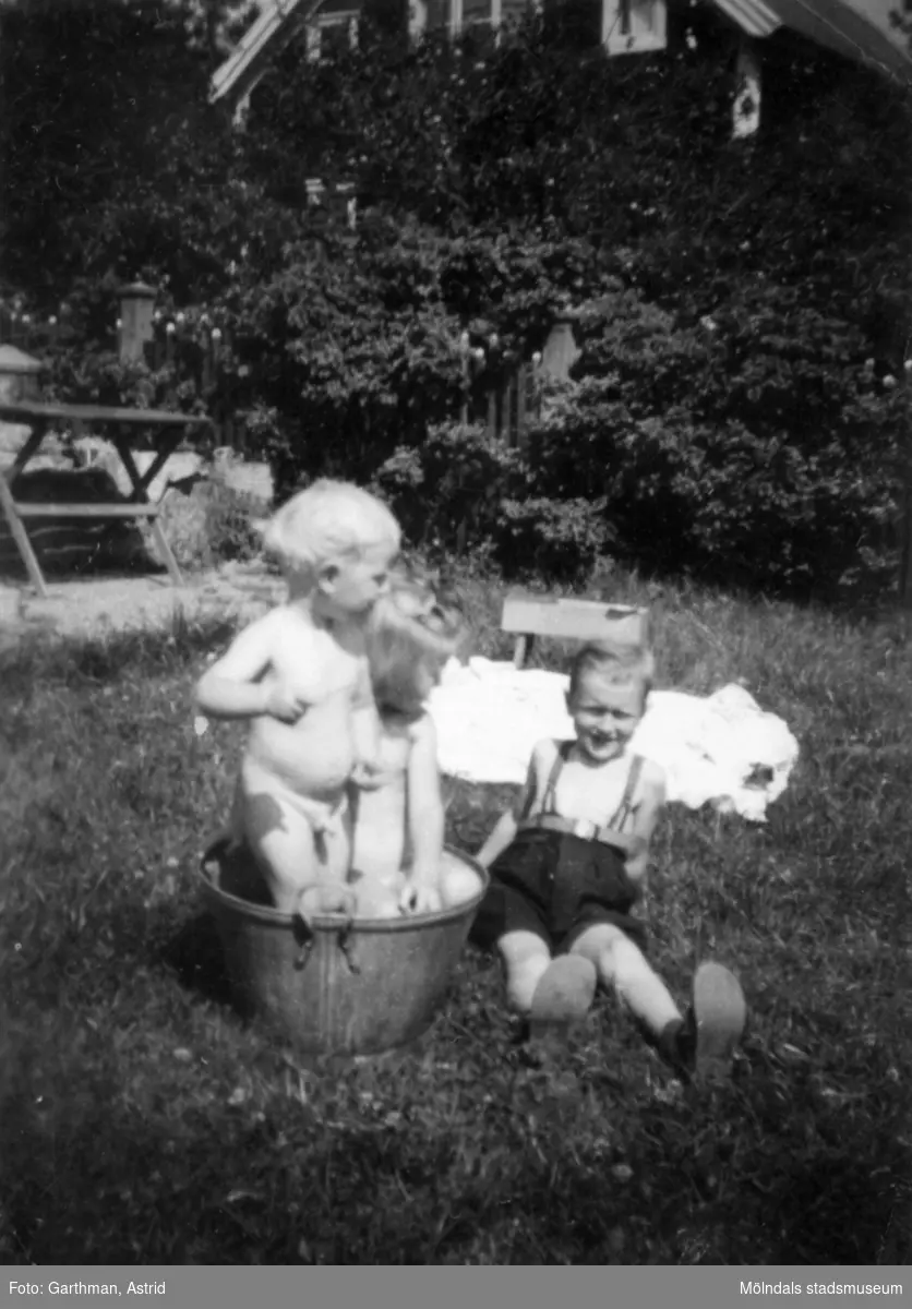 Syskonen Lars-Göran och Mari-Louis Gunnarsson badar i baljan och Leif-Åke Garthman sitter bredvid. Slutet av 1940-tal/ början av 50-tal.