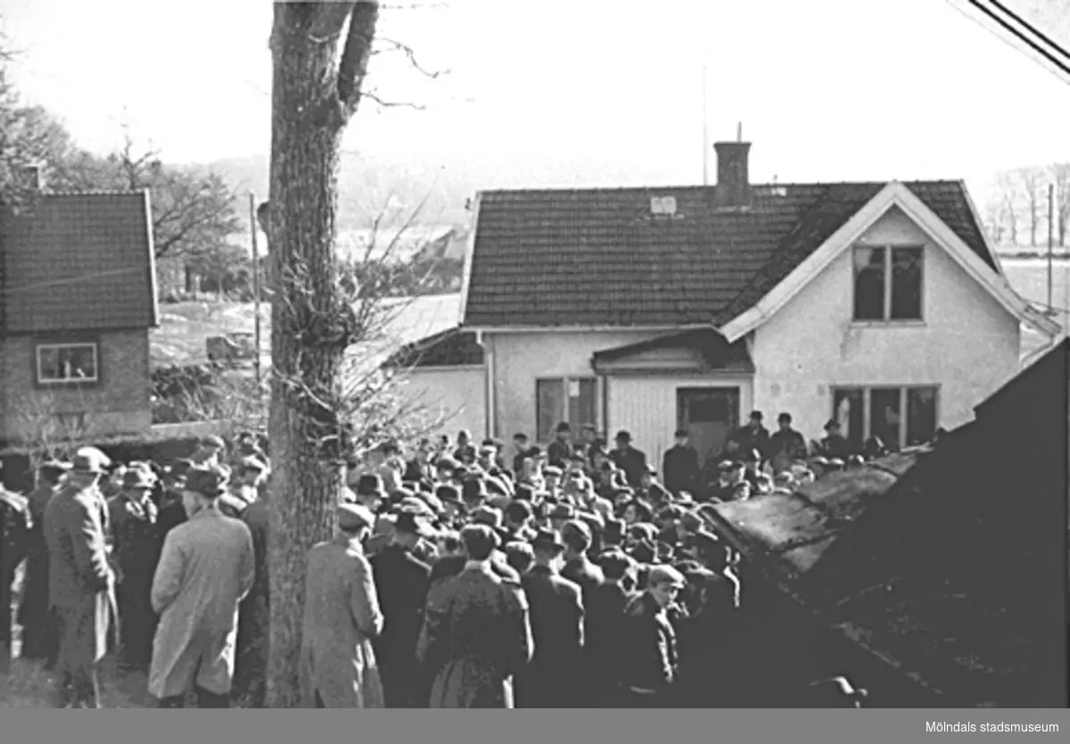 Lösöresauktion i Kållered 1940-tal. Flera män står samlade framför ett hus.