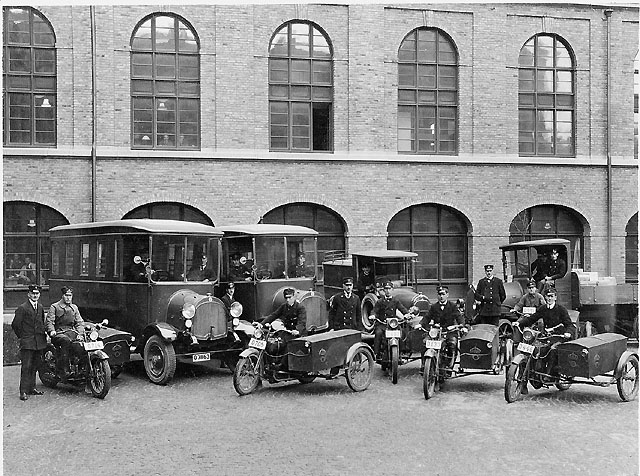 Postkontoret Göteborg 1, gården. Bilarna t.v. med "ribbstegar"
användes till utkörning av brevbärare i Göteborgs ytterområden.
Motorcykelförarna är lådtömmare. Foto troligen 1920-talet.