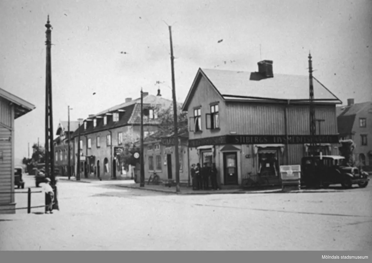Vy från Mölndalsbro mot söder på Kungsbackavägen (idag: Gamla Kungsbackavägen), 1930-tal. Till vänster: hörnet av Kungsbackavägen 1. Till höger: Larsson taxi. Övriga fastigheter är Kungsbackavägen 6 (E. & K. Karlssons järnhandel), 4 och 2 ("Stibergs hörna" Stibergs livsmedelshandel mellan Kungsbackavägen och Frölundagatan.