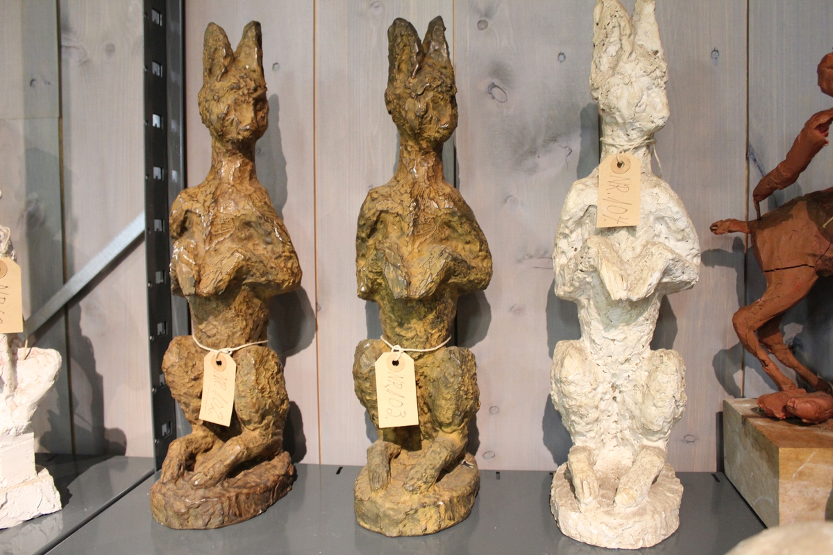 En skulptur i gips av en hare sittende på to. Se også nr. 102 og nr. 103.