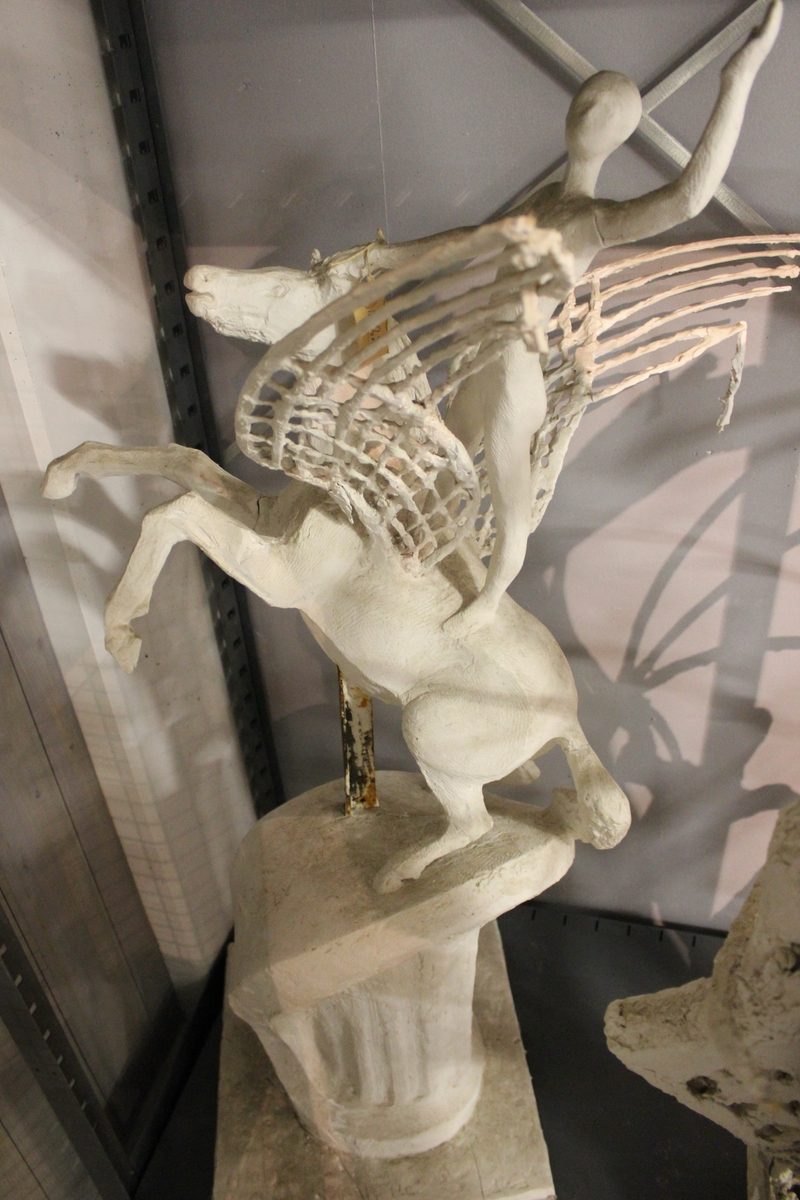 Skulptur i gips av en hest med vinger og en rytter. Tittel: "Vingehesten". Konkurranse utkast av Bjørnson monument. Motto: Over de høye fjelle". Se også nr.220.