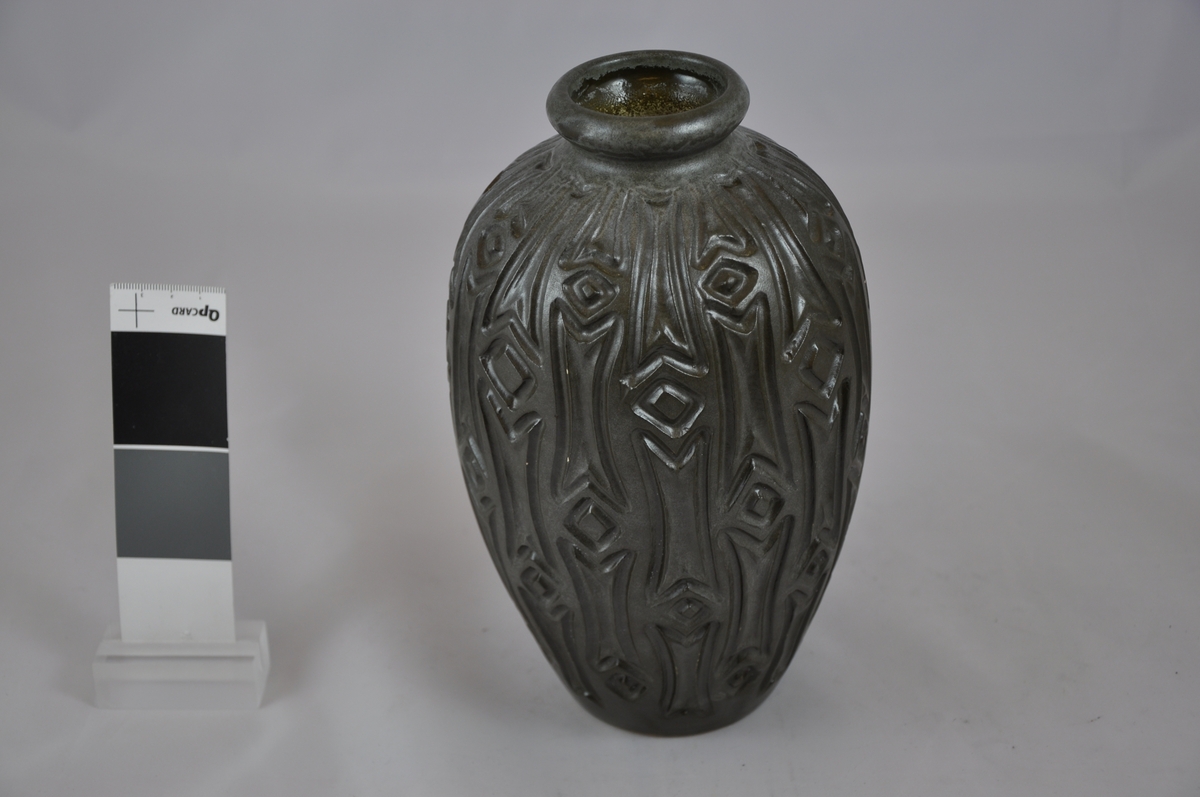 Rund vase som blir bredere mot midten. Vasen er dekorert med et mønster som består av streker og firkanter.
Åå undersiden av vasen finner man symbolet kk ( Kråkerøy keramikk) og tallet 547.