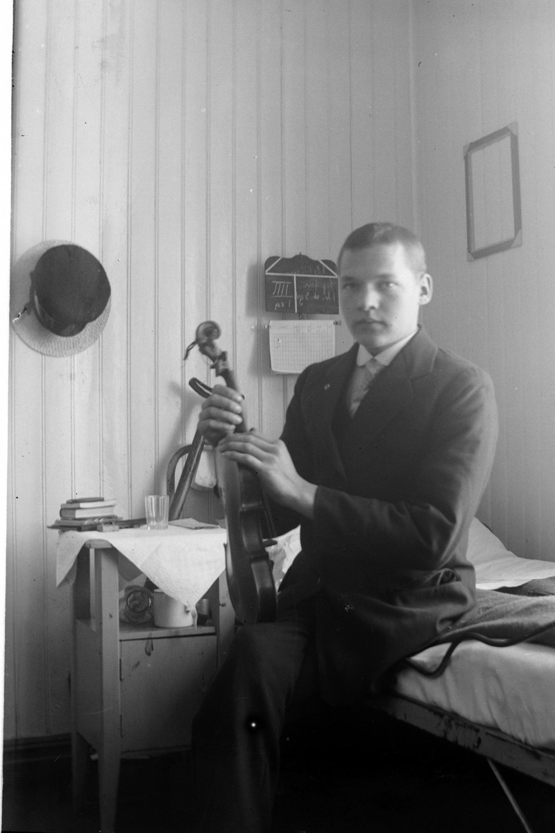 Gutt med fiolin, fotografert sittende på en seng. Bildet kan være fra sykehuset.